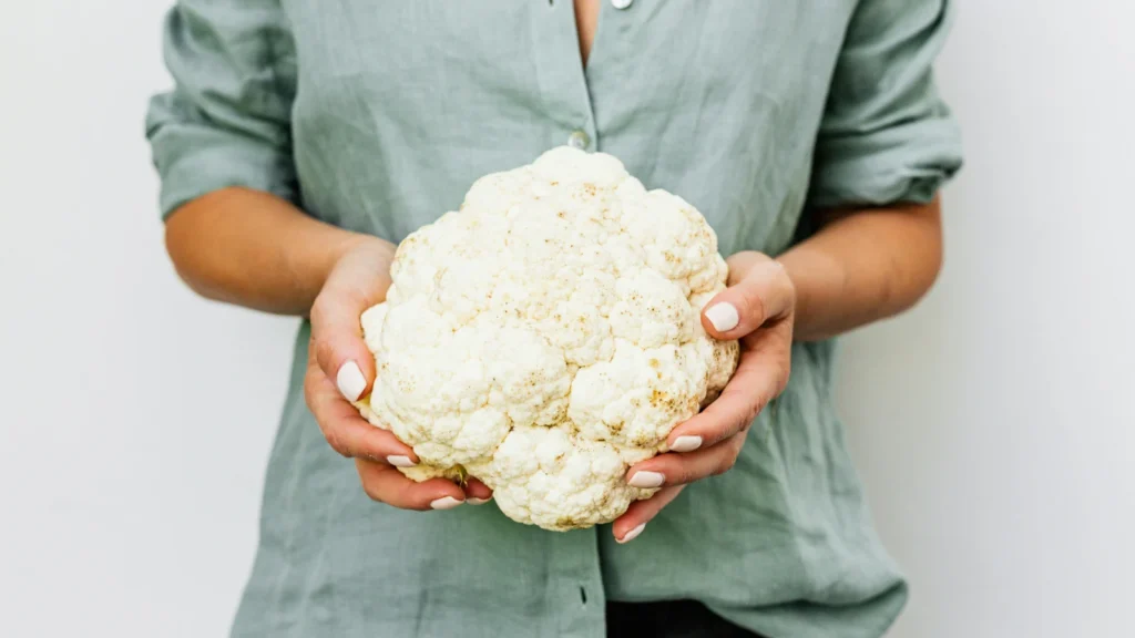 a woman holding a head of cauliflower